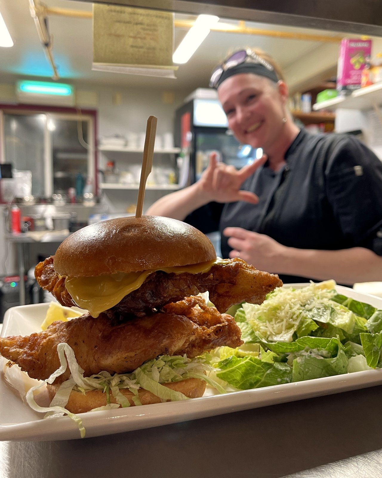 Kitchen lead Whitney shaka behind a Holy Ship fish burger and caesar salad, OV Burger Bar Prince Rupert