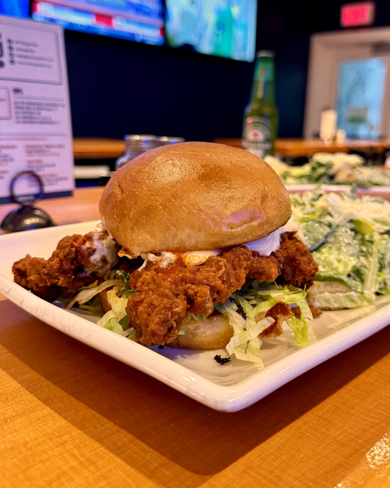 Buffalo fried chicken sandwich with ranch and buffalo sauce on a brioche bun, served with a Caesar salad at OV Burger Bar in Prince Rupert, BC